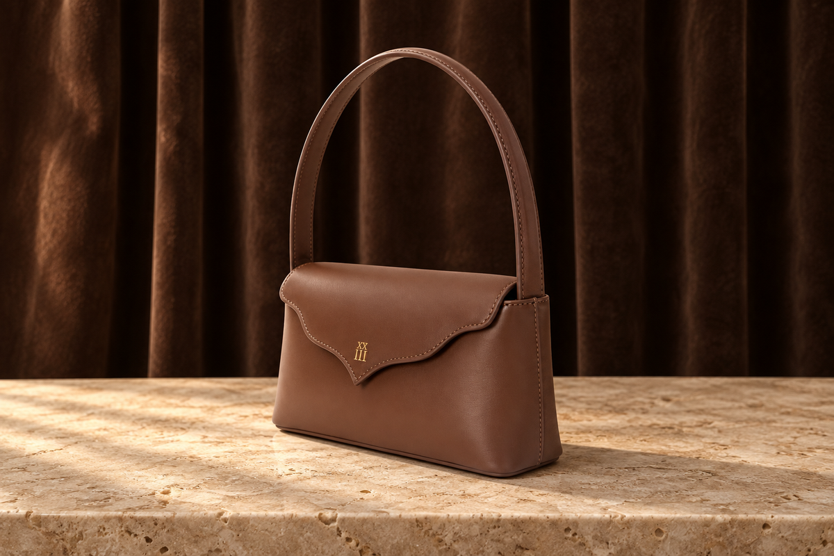 Élodie chocolate leather shoulder bag on travertine, editorial setting